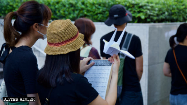 一名集会参与者手持千纸鹤表达声援香港民主抗争运动