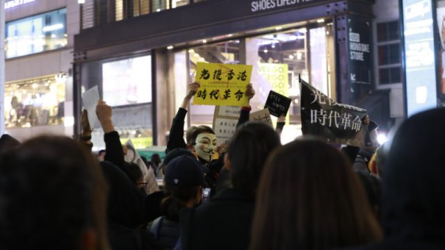 一名示威者在人群中高举标语牌:"光复香港时代革命"