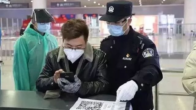 杭州火车东站内警察正在指导旅客用手机刷健康码