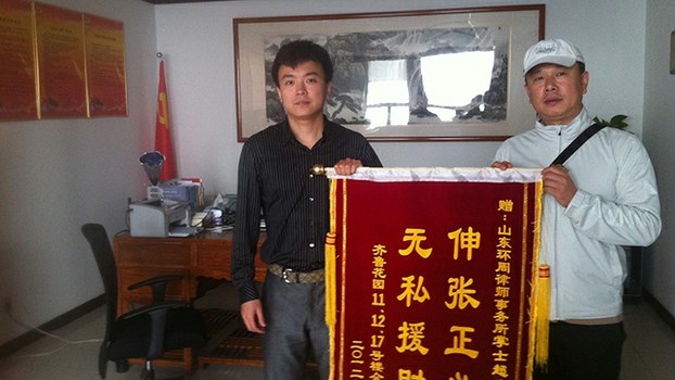 2012年，掌士超律师（左）接受一百余户小区业主赠送锦旗。