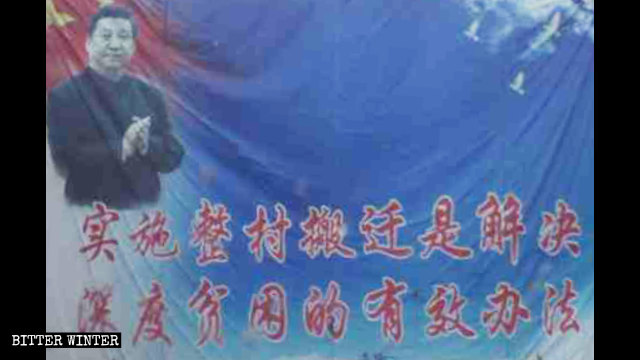 一居民楼旁悬挂的条幅写着：“实施整村搬迁是解决深度贫困的有效办法”